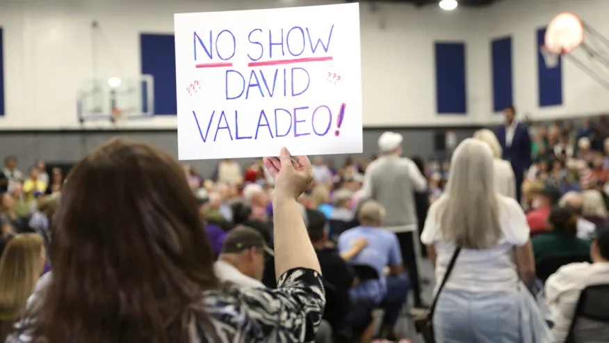 A woman holds a sign referring to her congressman, Rep. David Valadeo (R-Calif.), as Rep. Ro Khanna (D-Calif.) holds a town hall meeting at MLK Community Center in Bakersfield, Calif