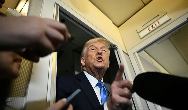 US President Donald Trump speaks to the press aboard Air Force One