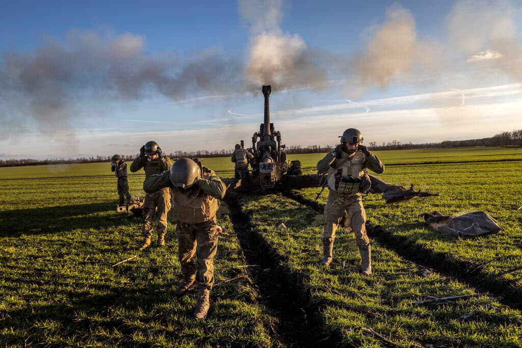 Ukrainian soldiers firing a howitzer at Russian armored vehicles