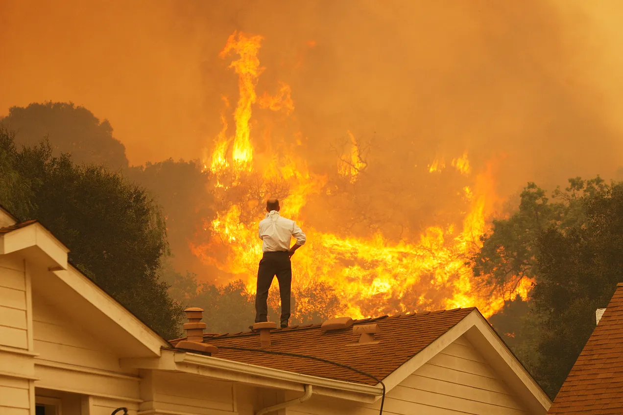 A man on a rooftop looks at flames as the Springs Fire approached on May 3, 2013 near Camarillo, California