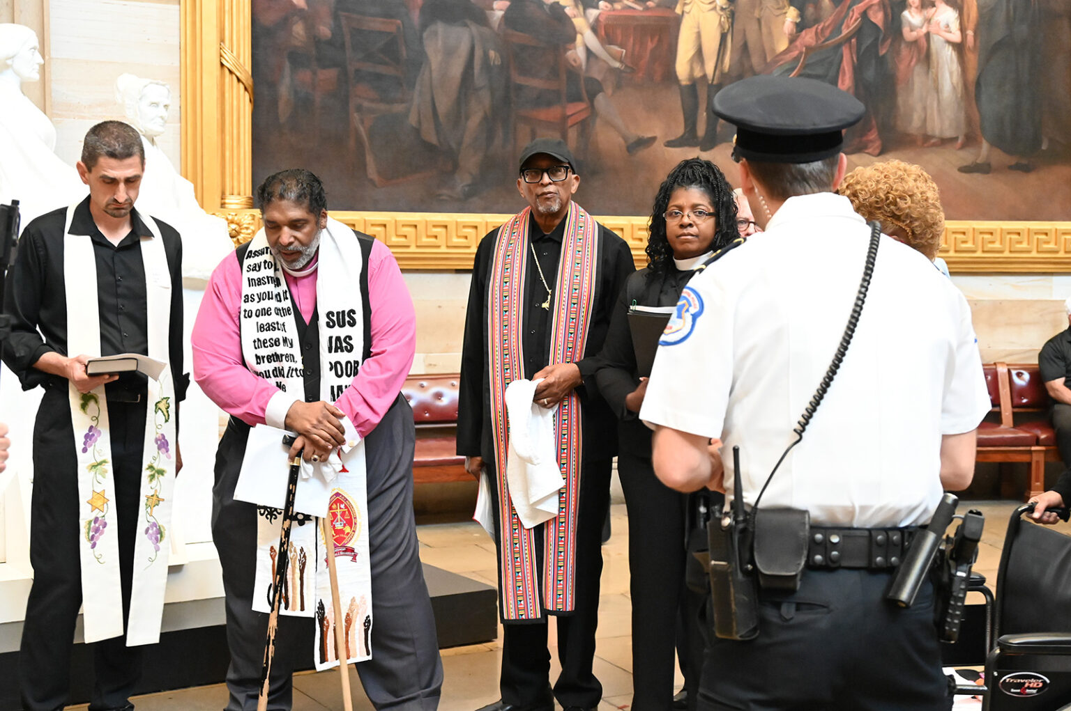 A police officer, right, stands near as the Rev. Jonathan Wilson-Hartgrove, from left, the Rev. William Barber II and others pray in the Capitol Rotunda, Monday, April 28, 2025, in Washington A police officer, right, stands near as the Rev. Jonathan Wilson-Hartgrove, from left, the Rev. William Barber II and others pray in the Capitol Rotunda, Monday, April 28, 2025, in Washington