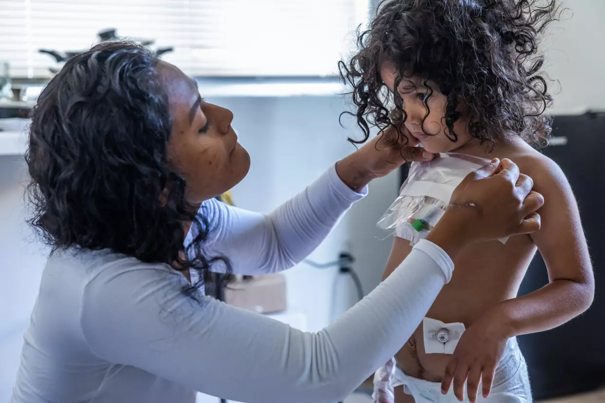 As part of her daily routine, Deysi Vargas covers up her daughter’s intravenous attachments with a plastic sheet and tape to prevent any infections before her morning shower and school in Bakersfield on May 23, 2025 As part of her daily routine, Deysi Vargas covers up her daughter’s intravenous attachments with a plastic sheet and tape to prevent any infections before her morning shower and school in Bakersfield on May 23, 2025