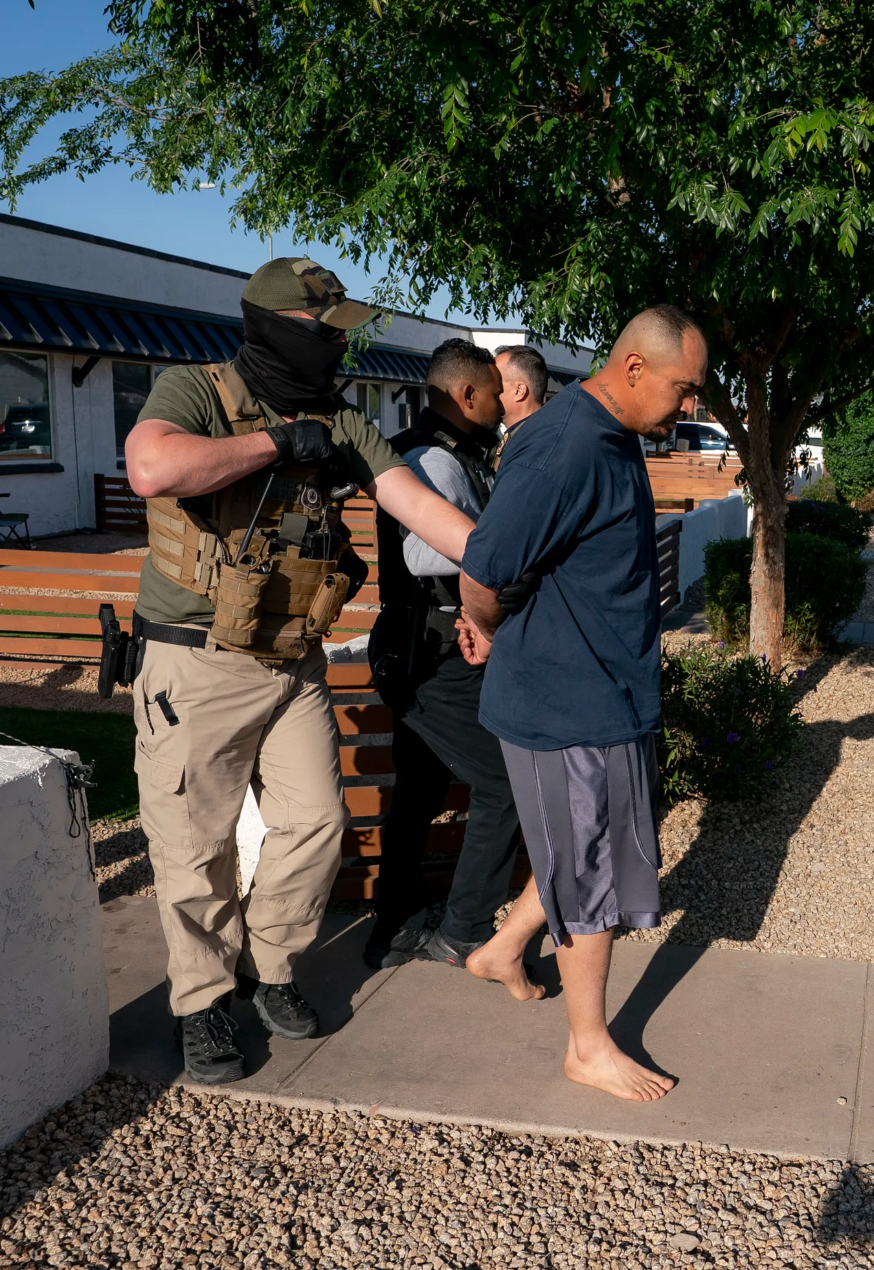 masked man detaining brown-skinned man