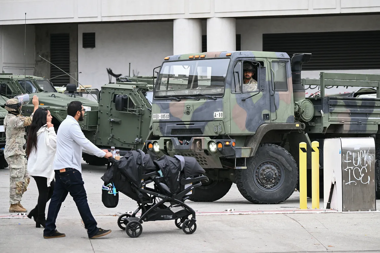 A couple pushes a stroller as members of the California National Guard stand watch outside the Edward R. Roybal Federal Building in LA on June 10. (Ronaldo Schemidt/AFP via Getty) A couple pushes a stroller as members of the California National Guard stand watch outside the Edward R. Roybal Federal Building in LA on June 10. (Ronaldo Schemidt/AFP via Getty)