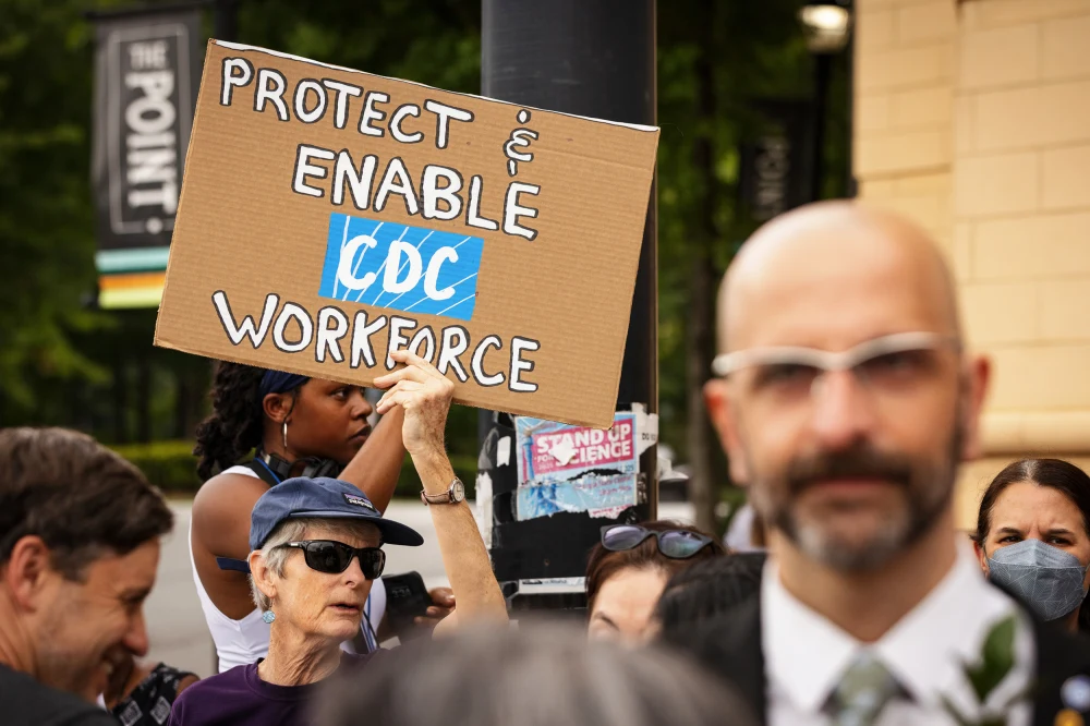 A demonstrator holds a sign behind Demetre Daskalakis, former director of the CDC's National Center for Immunization and Respiratory Diseases, outside the CDC headquarters in Atlanta on Aug. 28.Dustin Chambers / Bloomberg via Getty Images