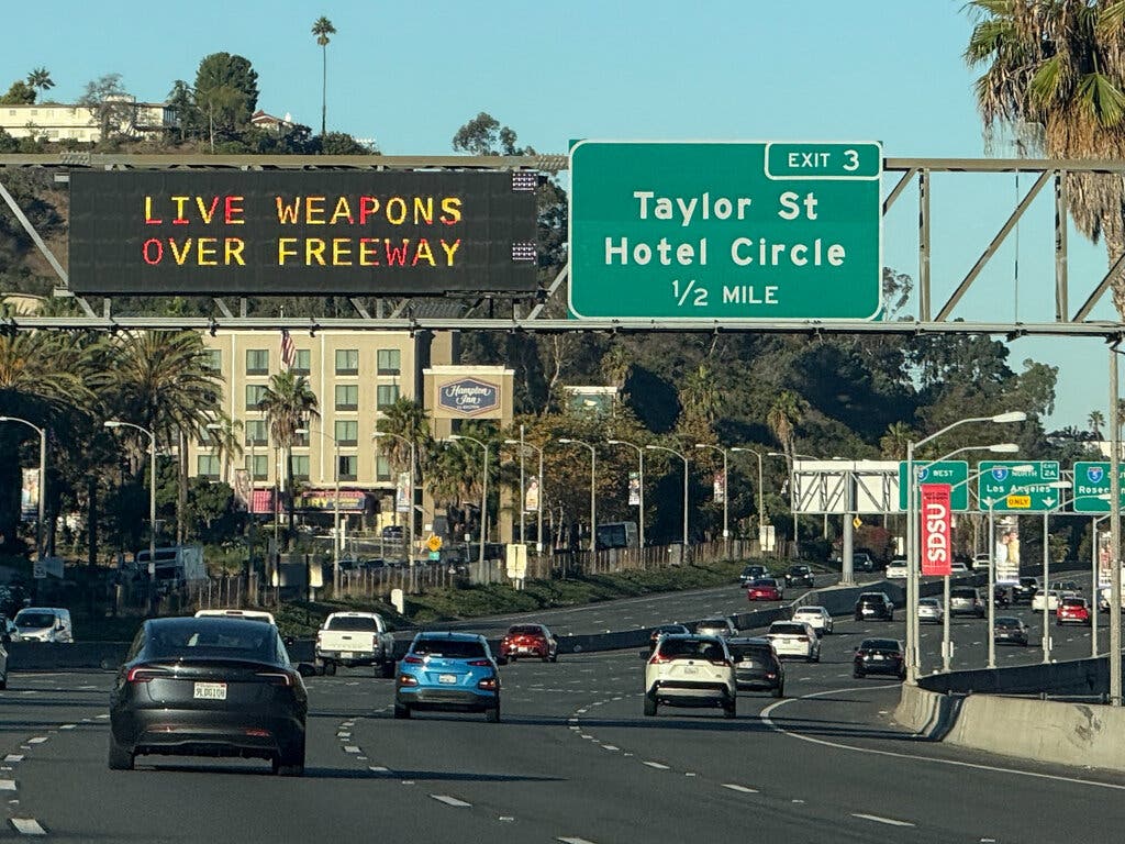 A warning over a highway near Interstate 5 alerted drivers about the military using live weapons on Saturday.Credit...Patrick Fallon/Agence France-Presse — Getty Images
