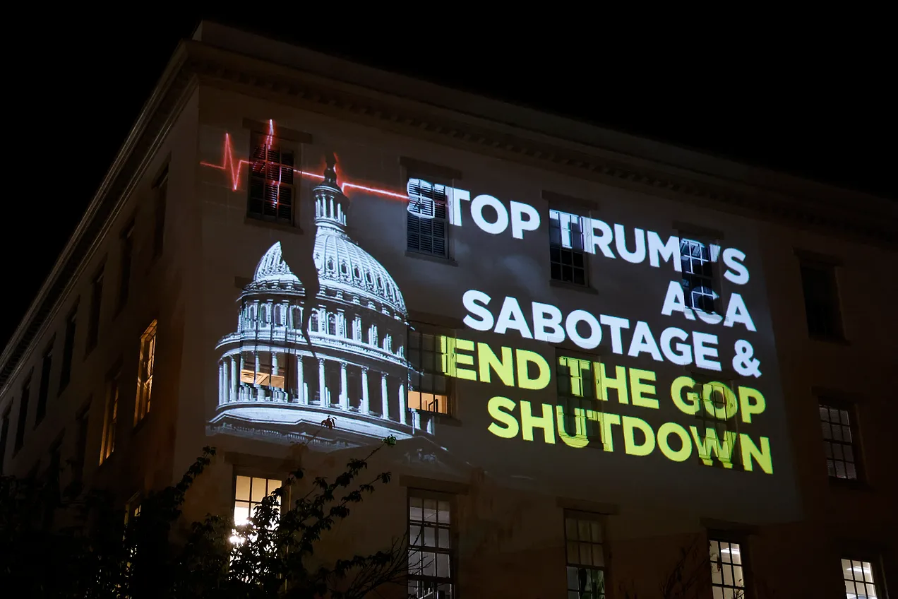 On the side of the Republican National Committee building in Washington, D.C., a projection urging the funding of health care and blaming the government shutdown on Donald Trump and his party, on October 1, 2025. (Photo by Paul Morigi/Getty Images for Protect Our Care)