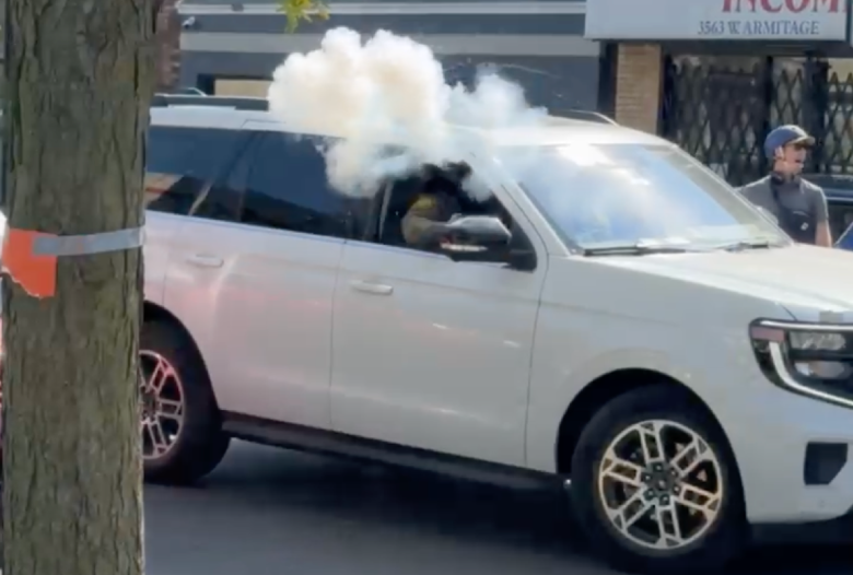 A masked agent threw a smoke grenade onto a crowded street in Chicago's Logan Square neighborhood Friday afternoon. Credit: Andrew Denton