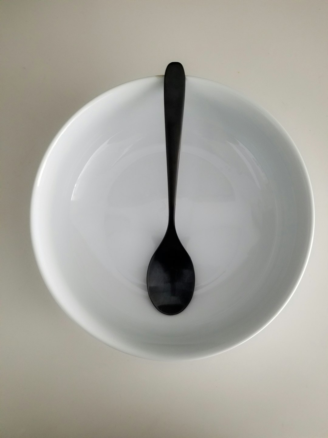 stainless steel spoon on white ceramic plate stainless steel spoon on white ceramic plate