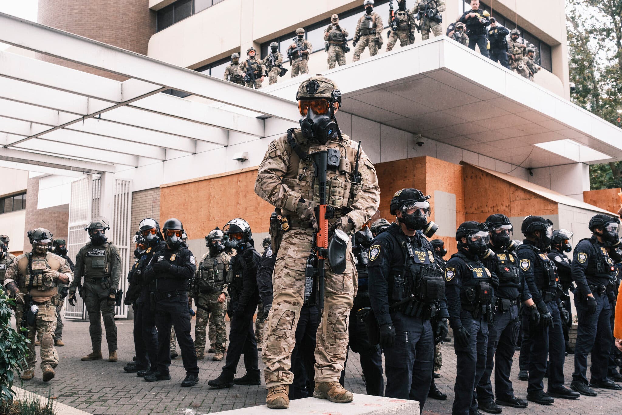 Law enforcement officers guarding a federal immigration center in Portland, Ore., during protests last month.Credit...Jordan Gale for The New York Times
