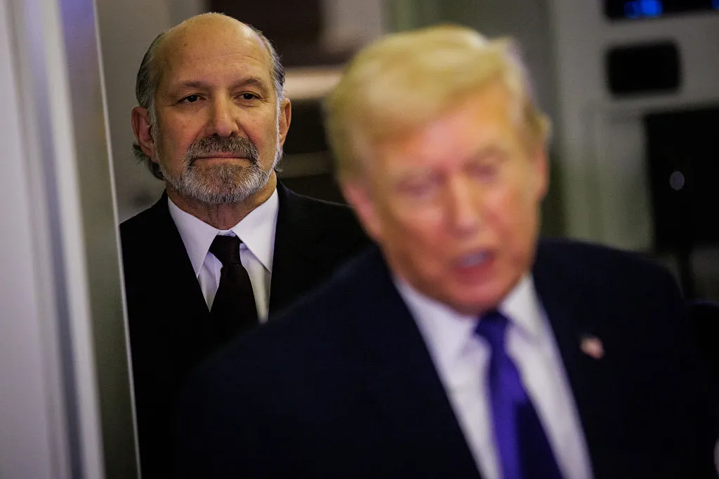 U.S. Secretary of Commerce Howard Lutnick stands behind U.S. President Donald Trump aboard Air Force One on February 6, 2026. (Photo by Samuel Corum/Getty Images)