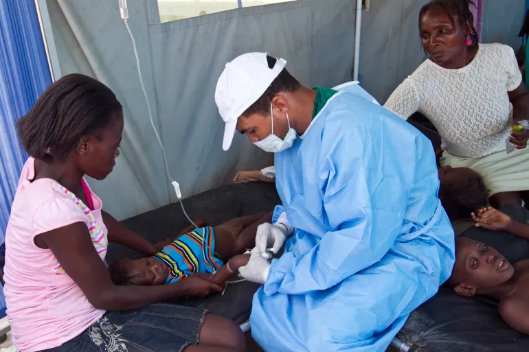 A cholera patient is treated with an IV solution administered by a Cuban doctor at a hospital in L'Estere, Haiti, on October 26, 2010 [File: Sophia Paris/Minustah via Getty Images]