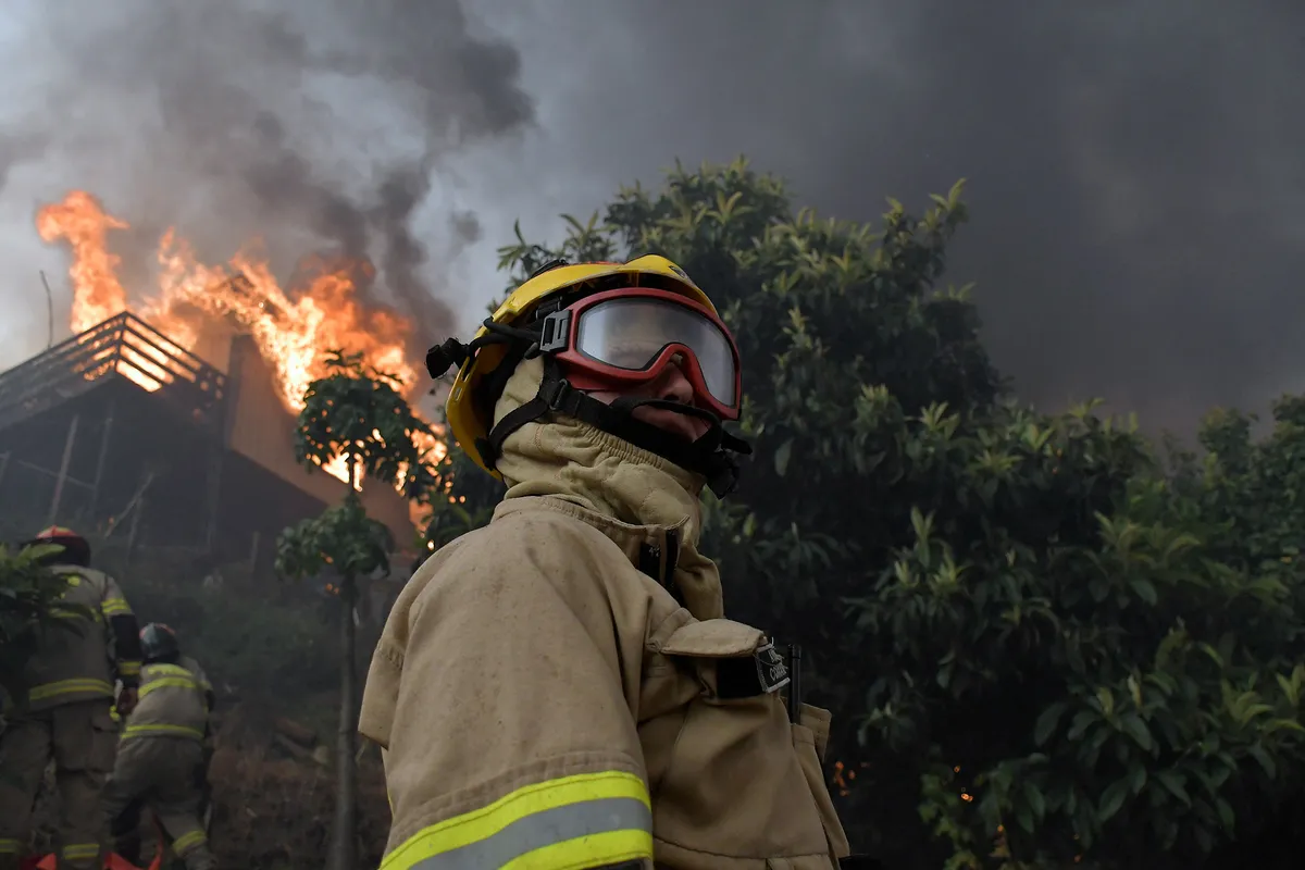 Firefighters try to extinguish a burning house during a wildfire in Chile in January.Photographer: Guillermo Salgado/AFP/Getty Images