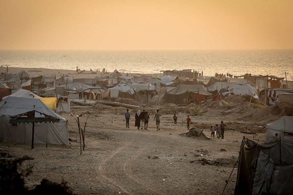 People walk through a camp of makeshift tents along Gaza's coastline in Gaza City, Gaza Strip, on November 10, 2025.