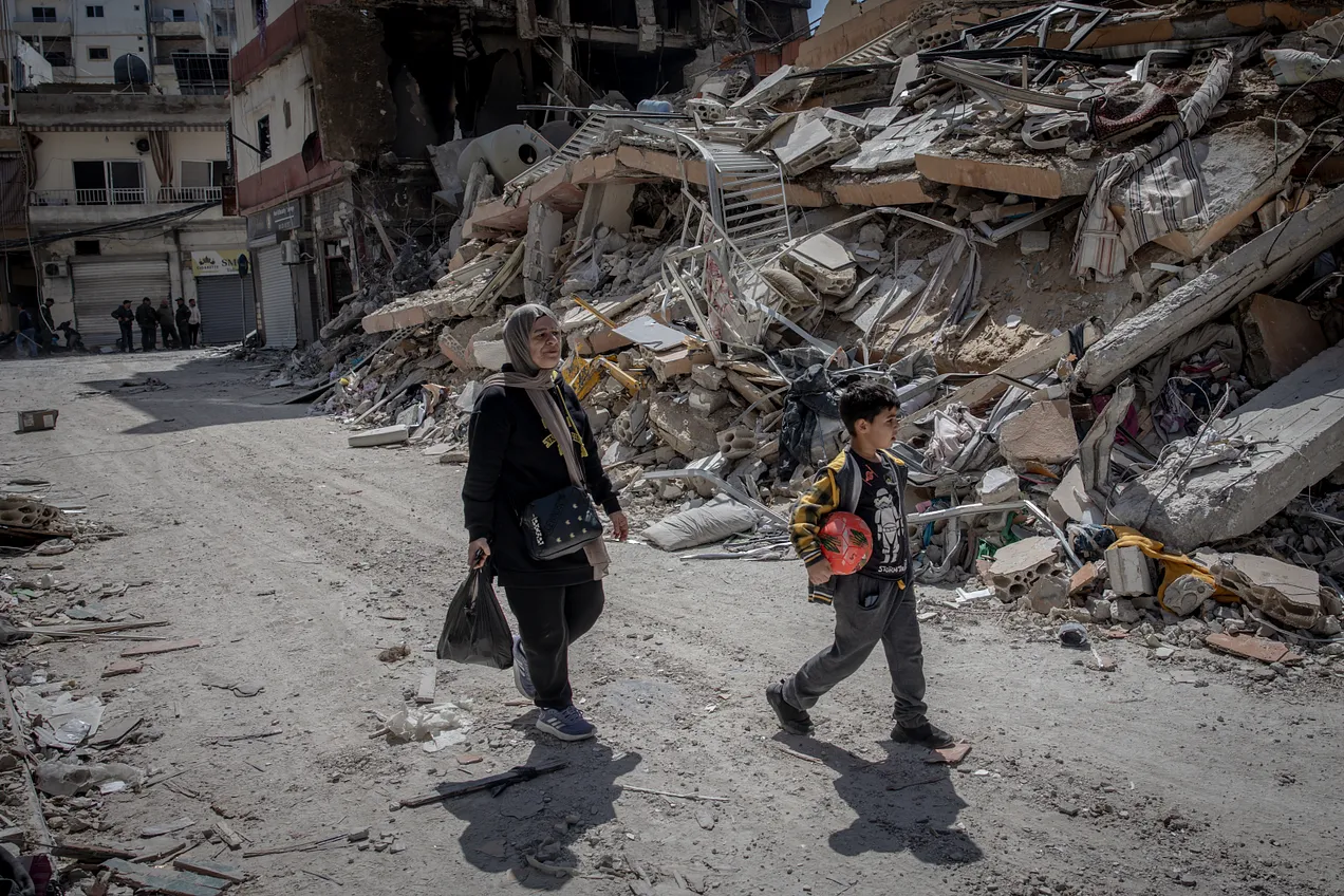 People walk past rubble from a destroyed building after an Israeli airstrike on April 10, 2026, in Tyre, Lebanon. Photo by Chris McGrath/Getty Images