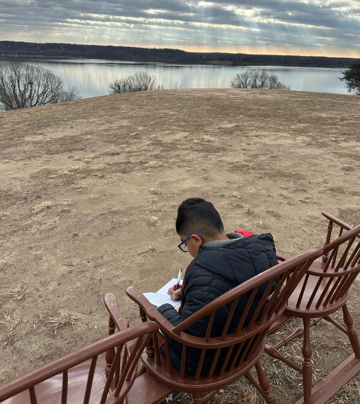 The author's son Tayz writing while sitting in a rocking chair at Mt. Vernon, outside George Washington's home.Courtesy of Ami J. Shah