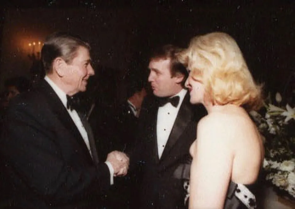 Ronald Reagan shaking hands with Donald Trump. Ivana Trump is standing beside.