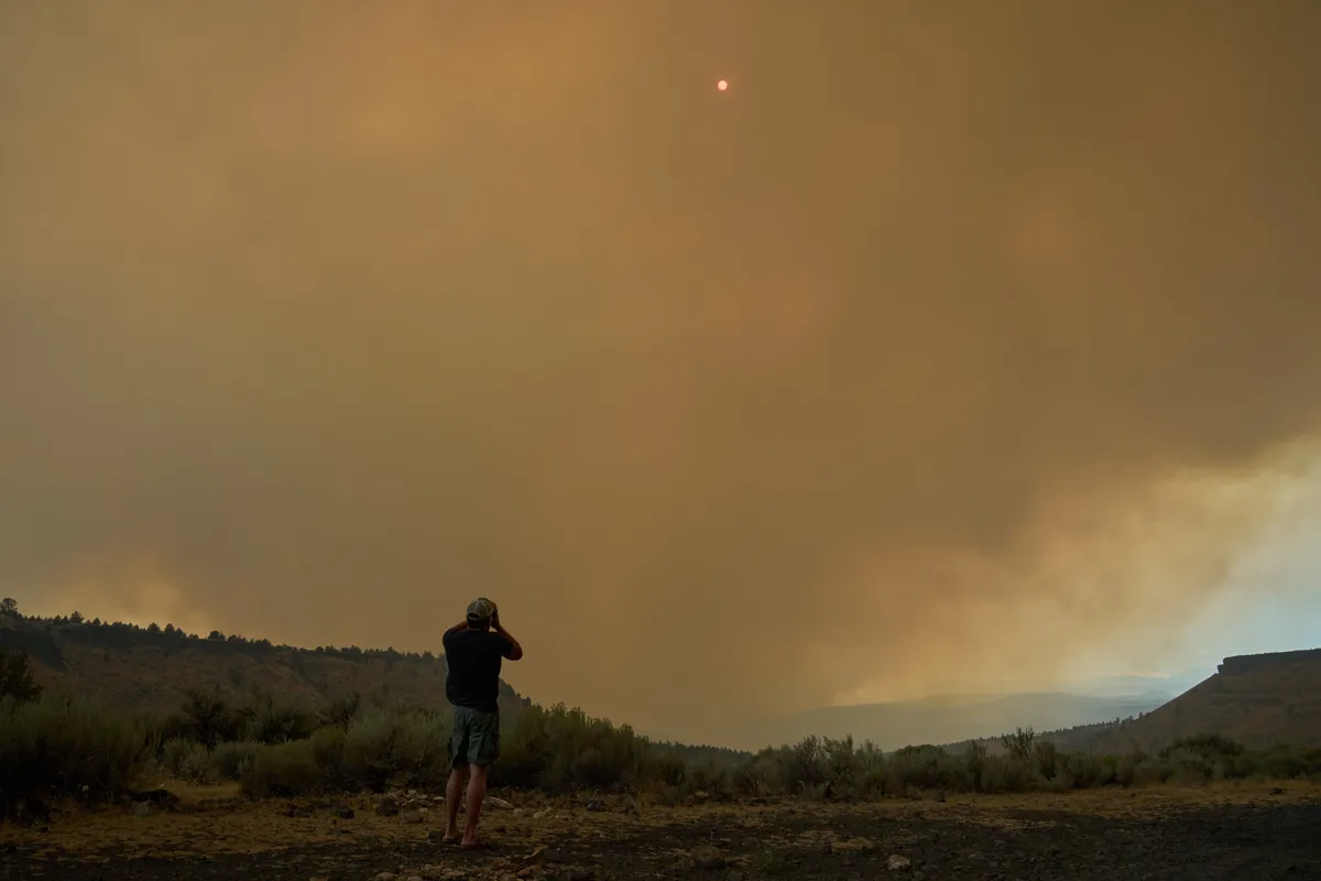 A Portland resident takes a picture of smoke from the Bench and Beachcomb fires along Highway 26 near Madras, Oregon, on July 25