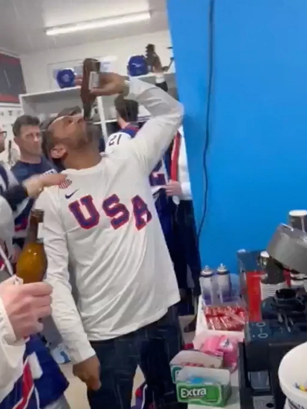 Kash Patel drinks a beer in front of hockey players