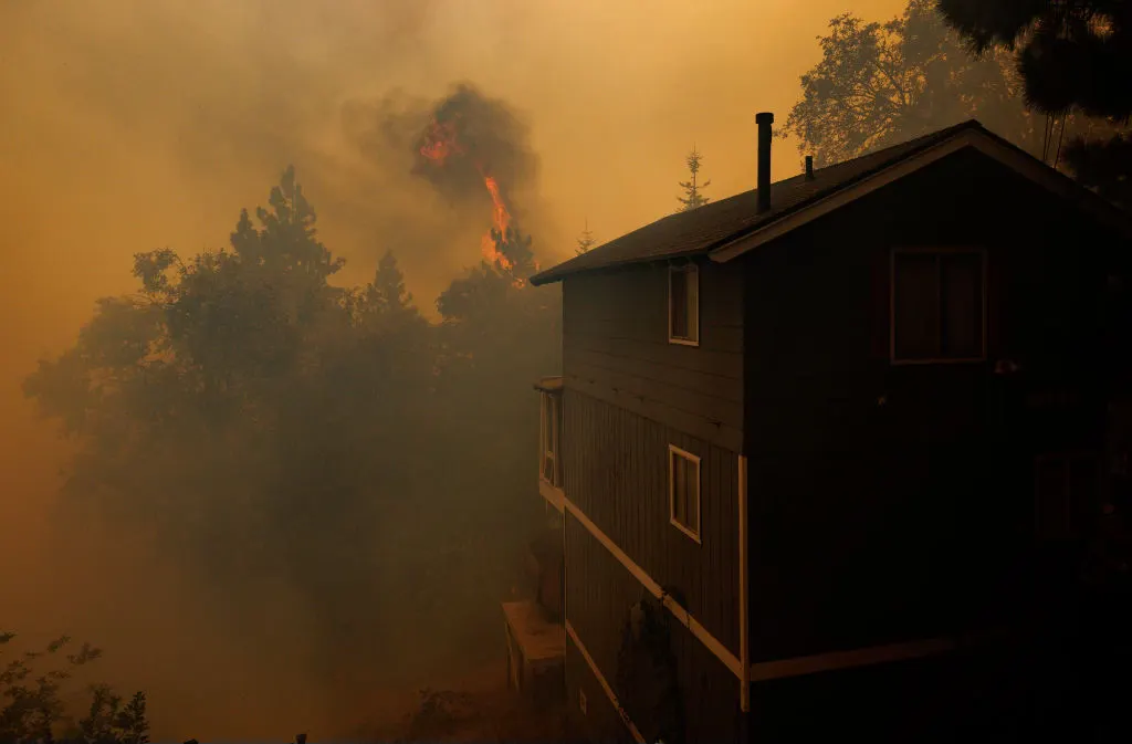 Flames burn close to a home as the Line fire burns into a tree lined neighborhood on September 10, 2024 in Running Springs, California. (Gina Ferazzi / Los Angeles Times via Getty Images)