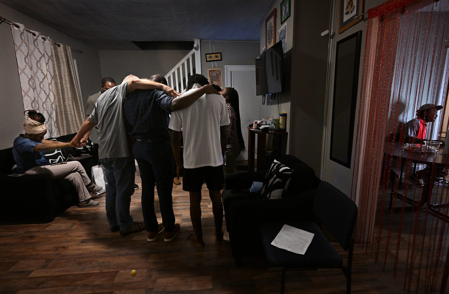 People pray with grieving family members of Pierre Damas Bel, 20, who died earlier in the day on Aug. 31, 2026, in Springfield, Ohio. (RNS photo/Carol Guzy)