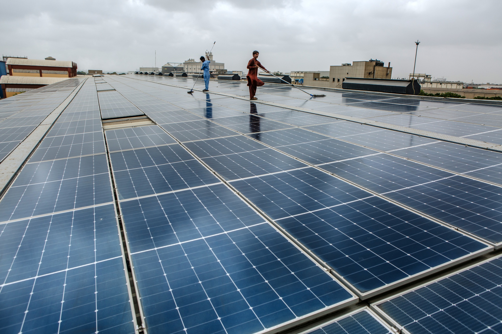 Workers clean rooftop solar panels at the Bin Qasim Packages plant in the Bin Qasim Industrial Zone in Karachi.Photographer: Asim Hafeez/Bloomberg